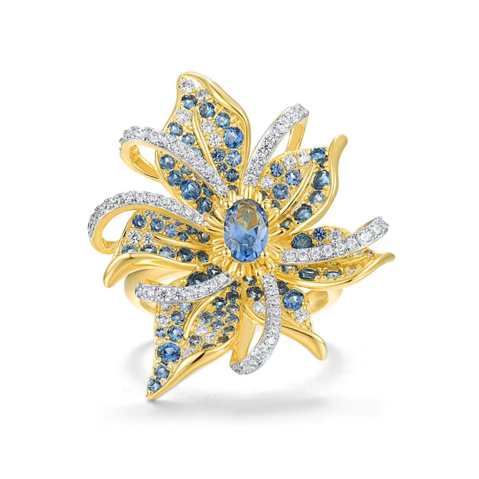Gold ring in the shape of a flower with pavé blue and white stones and a central oval gem

