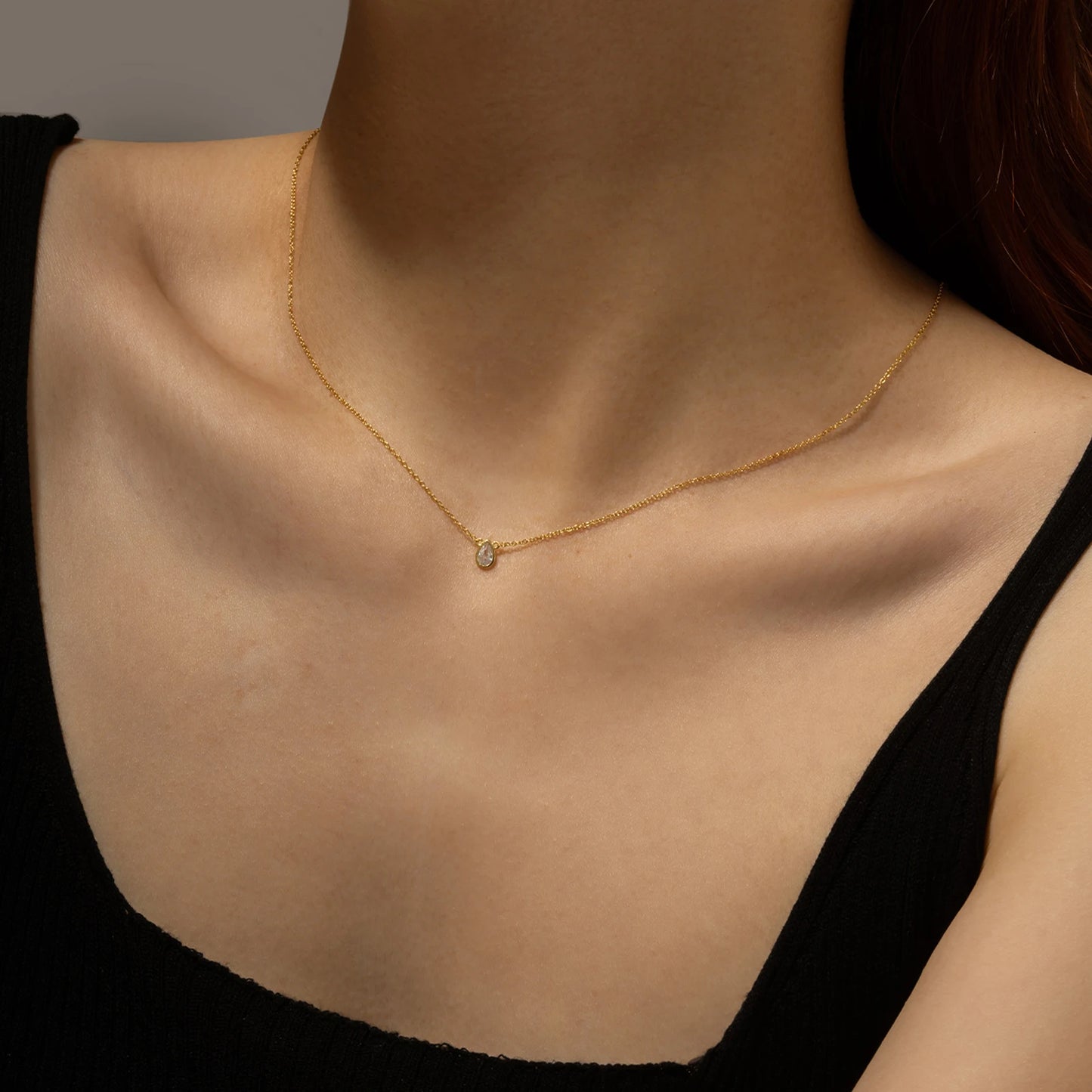 Gold chain necklace featuring a pear-shaped deep blue gemstone in a bezel setting