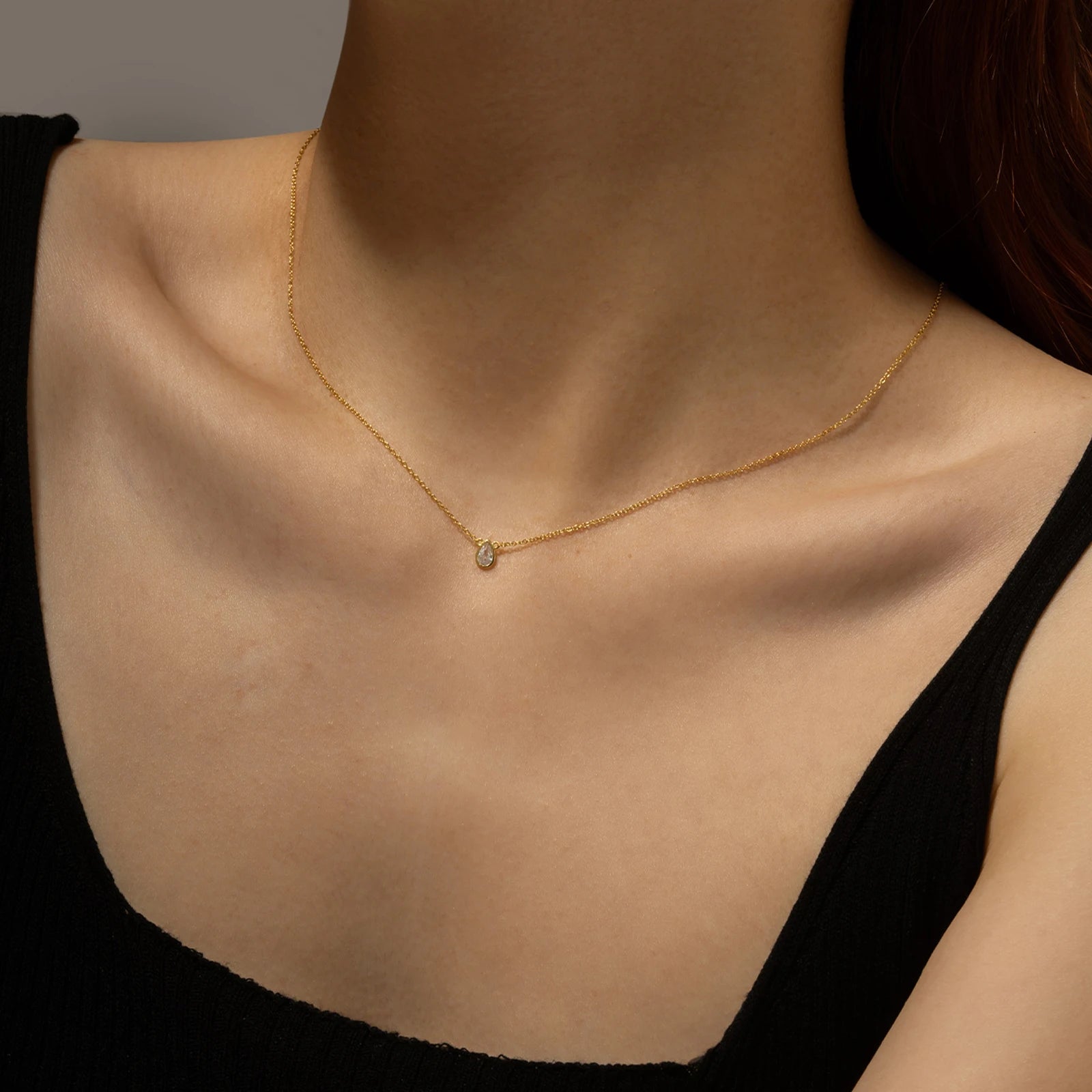 Gold chain necklace featuring a pear-shaped deep blue gemstone in a bezel setting