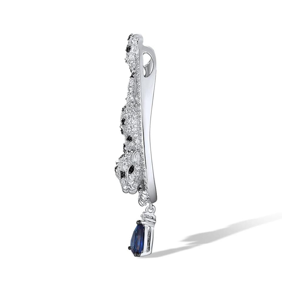 Leopard-shaped silver pendant with black stone spots, set within a teardrop frame and finished with a hanging blue teardrop gemstone.

