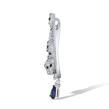 Leopard-shaped silver pendant with black stone spots, set within a teardrop frame and finished with a hanging blue teardrop gemstone.

