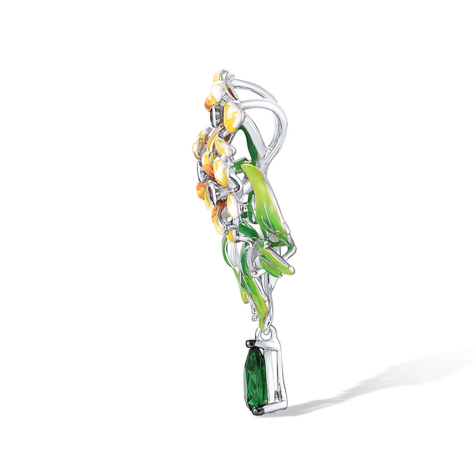 Brooch with three yellow enamel flowers, green enamel leaves, and a dangling green teardrop gemstone

