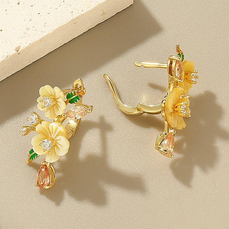 Yellow floral earrings with gemstone drops and green enamel leaves on gold setting

