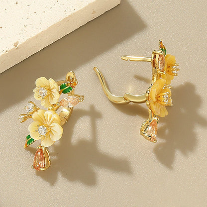 Yellow floral earrings with gemstone drops and green enamel leaves on gold setting

