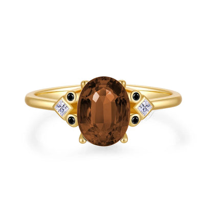Gold ring with large oval brown gemstone and black and white accent stones

