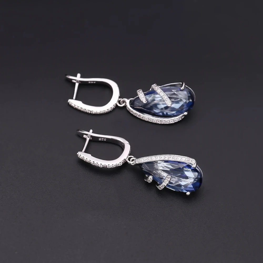 Silver earrings with faceted blue teardrop stones and delicate pavé accents

