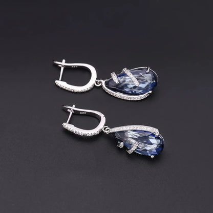 Silver earrings with faceted blue teardrop stones and delicate pavé accents

