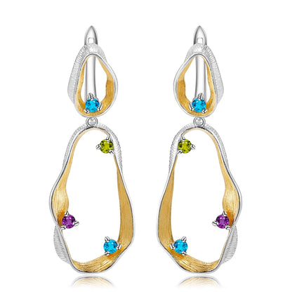 Dangling earrings with flowing gold and silver forms set with turquoise-colored stones

