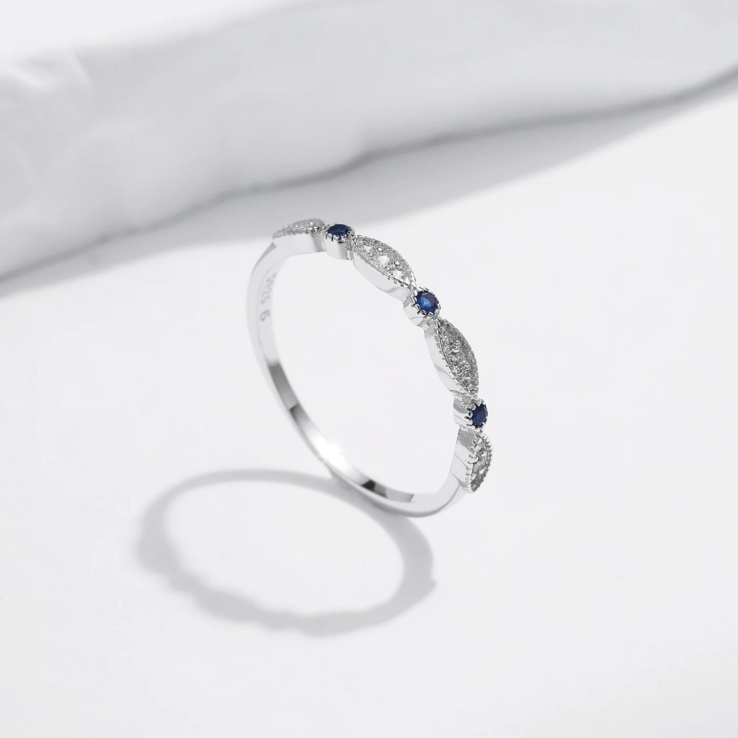 Sterling silver band with alternating marquise shapes and small round blue and clear stones

