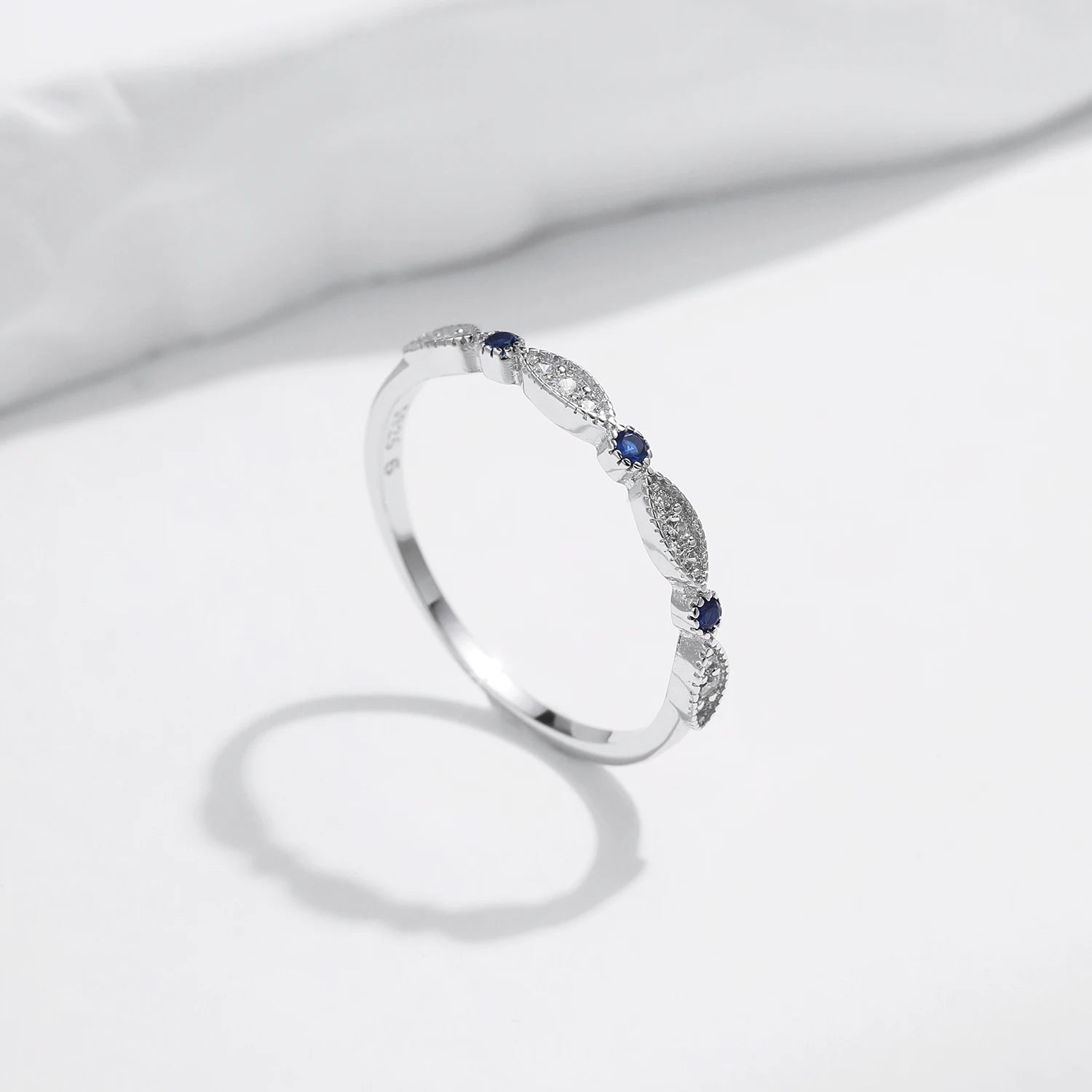 Sterling silver band with alternating marquise shapes and small round blue and clear stones


