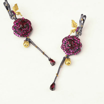 Long black rose earrings with red gemstones, gold leaves, and bud details from the Rossa Collection.

