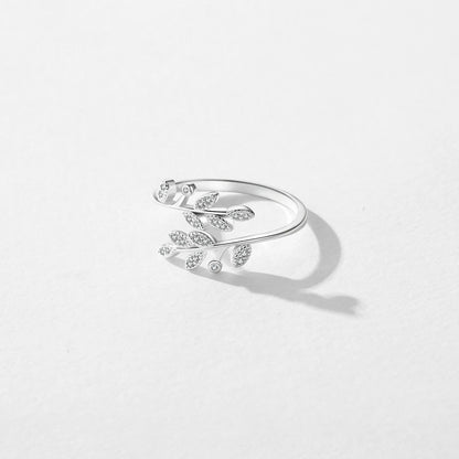 Silver ring designed with two curved branches, each adorned with pavé-set leaf shapes and tiny round white stones.


