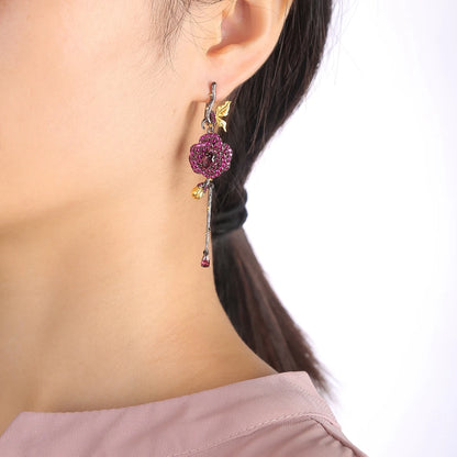 Long black rose earrings with red gemstones, gold leaves, and bud details from the Rossa Collection.

