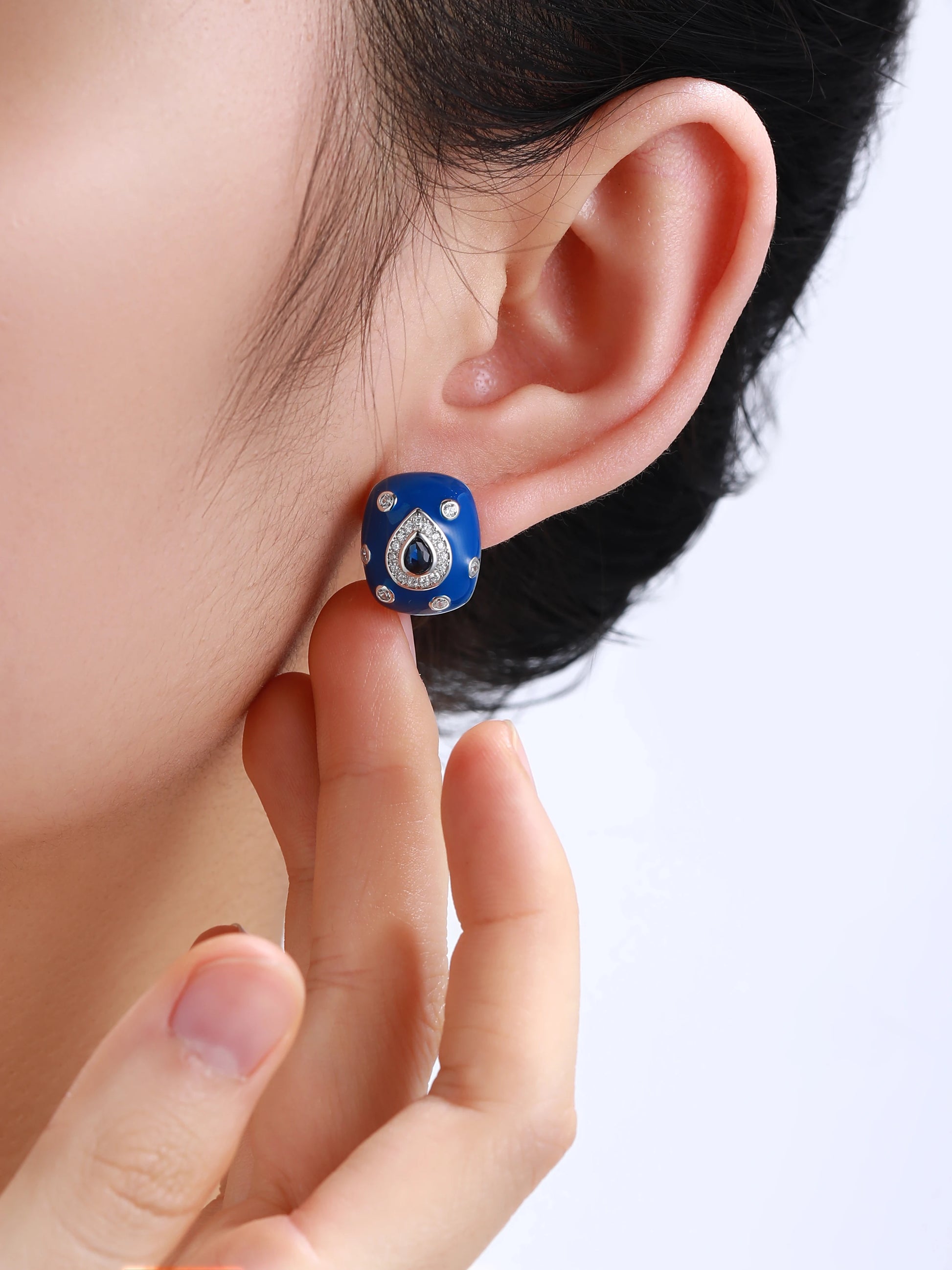 Bold blue enamel earrings with central teardrop-shaped sapphire stones framed by white zircon pavé on a silver base.

