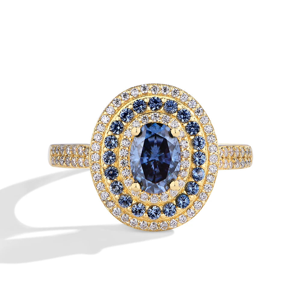 Sterling silver ring with an oval-cut deep blue gemstone surrounded by two concentric halos of white and blue stones, set on a pavé band