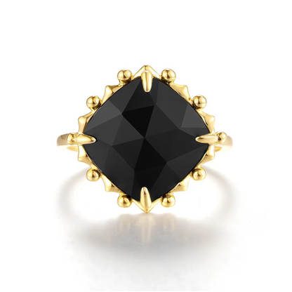 Gold ring with a large cushion-cut black stone and decorative claw prongs.


