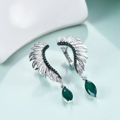 Silver earrings with feather-like design, green gemstones, and marquise green dangles

