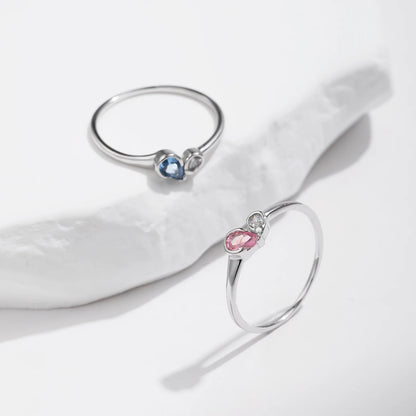 Sterling silver ring with a pear-shaped blue stone and round white stone set side by side
Sterling silver ring featuring a pink teardrop stone paired with a round clear stone in an open-heart inspired setting.


