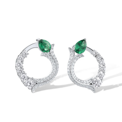 Silver earrings with circular diamond pave design and pear-shaped green jade stones at the top

