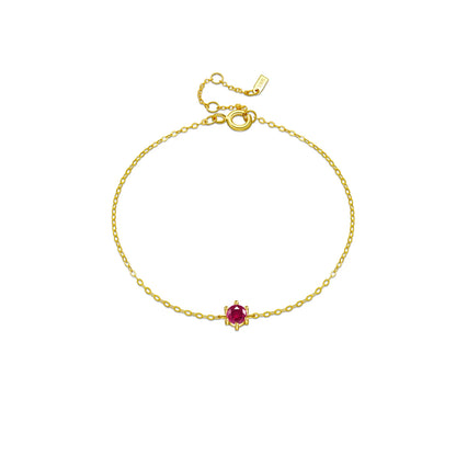 Delicate silver bracelet featuring a single round red stone set at the center.

