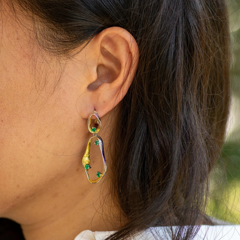Dangling earrings with flowing gold and silver forms set with turquoise-colored stones

