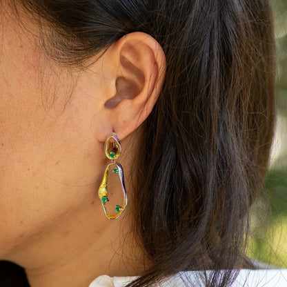 Dangling earrings with flowing gold and silver forms set with turquoise-colored stones

