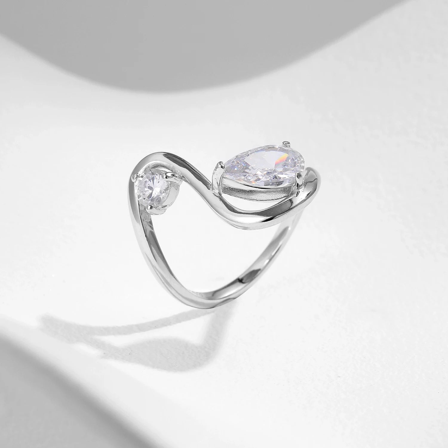 Sterling silver bypass ring featuring two white round-cut stones in a modern flowing design

