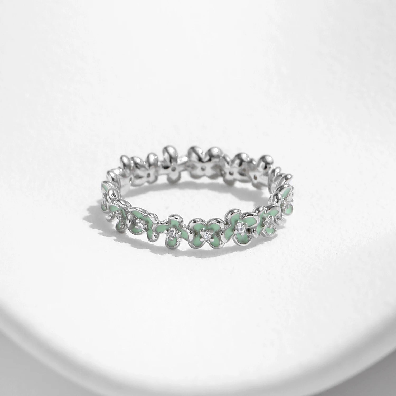 Sterling silver floral band ring with light green enamel petals and tiny diamond accents.

