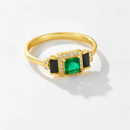 Gold ring with square green center stone, black accents, and pavé border

