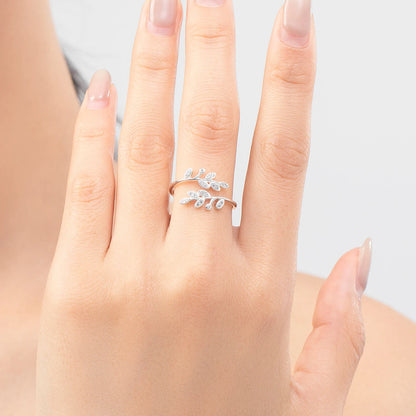 Silver ring designed with two curved branches, each adorned with pavé-set leaf shapes and tiny round white stones.

