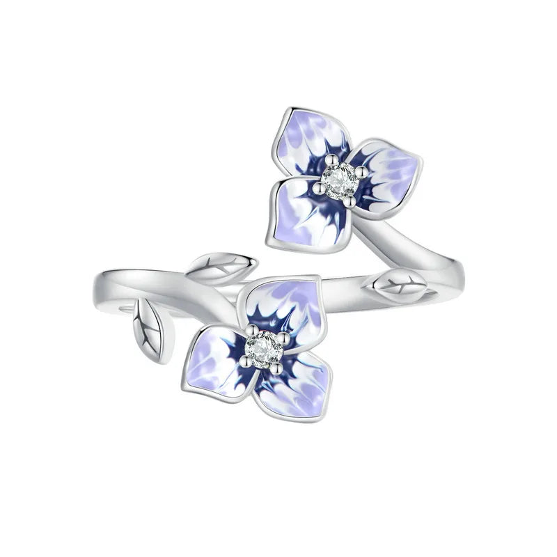 Sterling silver wrap ring featuring two delicate purple and white enamel flowers with clear center stones and leaf details.

