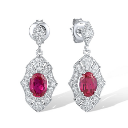 Rubino earrings with deep red oval stones framed in intricate silver settings accented by small white crystals.

