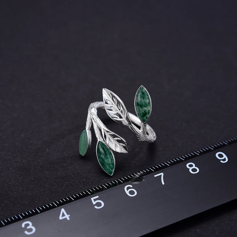 Adjustable silver ring featuring green marbled leaf accents in an open branch design.

