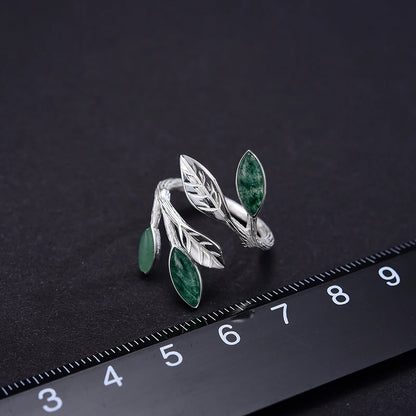 Adjustable silver ring featuring green marbled leaf accents in an open branch design.

