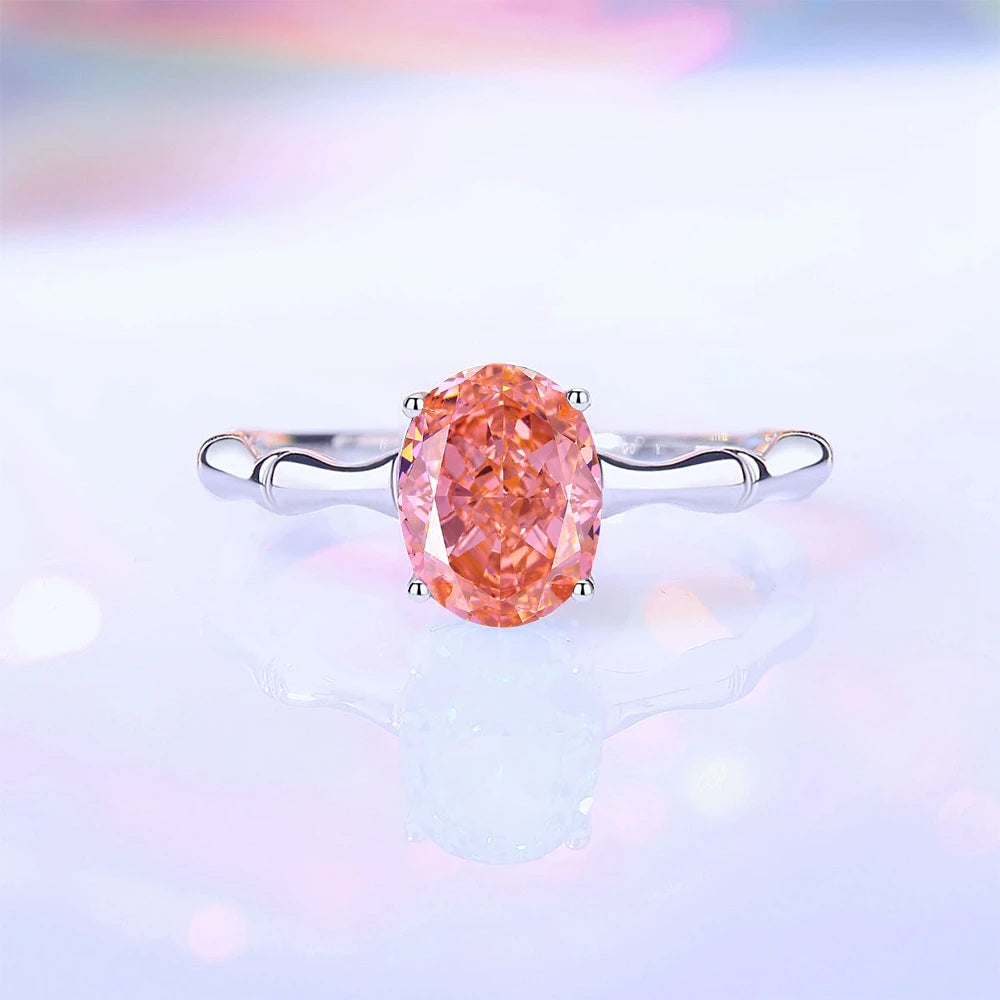 Silver band ring with an oval-cut pink-orange tourmaline stone, displayed against a deep red background from the Rossa collection.

