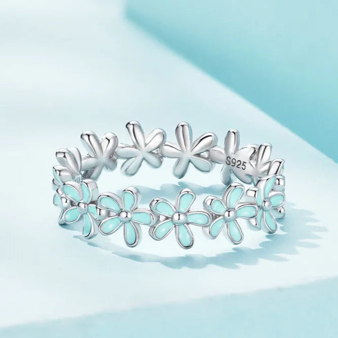 Silver floral band ring with alternating blue enamel and plain silver daisy motifs

