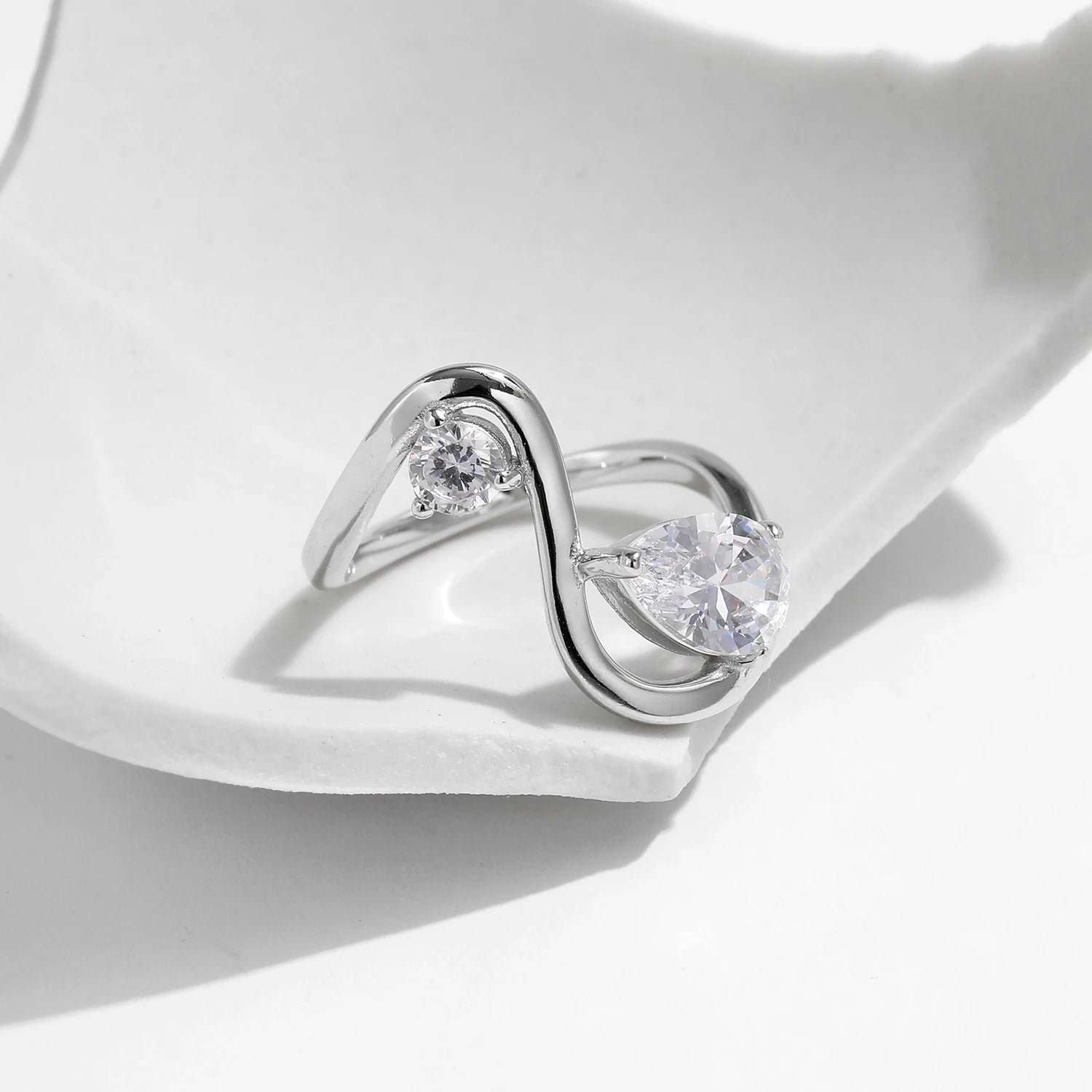 Sterling silver bypass ring featuring two white round-cut stones in a modern flowing design

