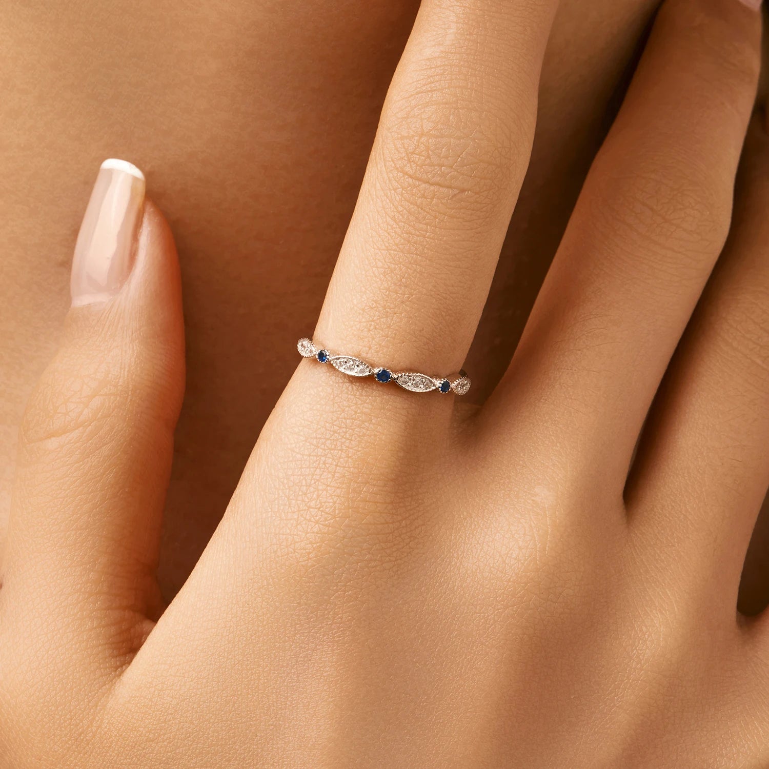Sterling silver band with alternating marquise shapes and small round blue and clear stones

