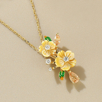Yellow flower pendant necklace with gemstone accents and green enamel leaf details

