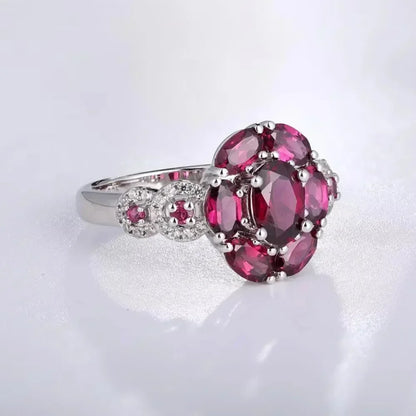 Silver ring featuring a bold cluster of deep red oval gemstones, framed by smaller accents, from the Rossa Collection.


