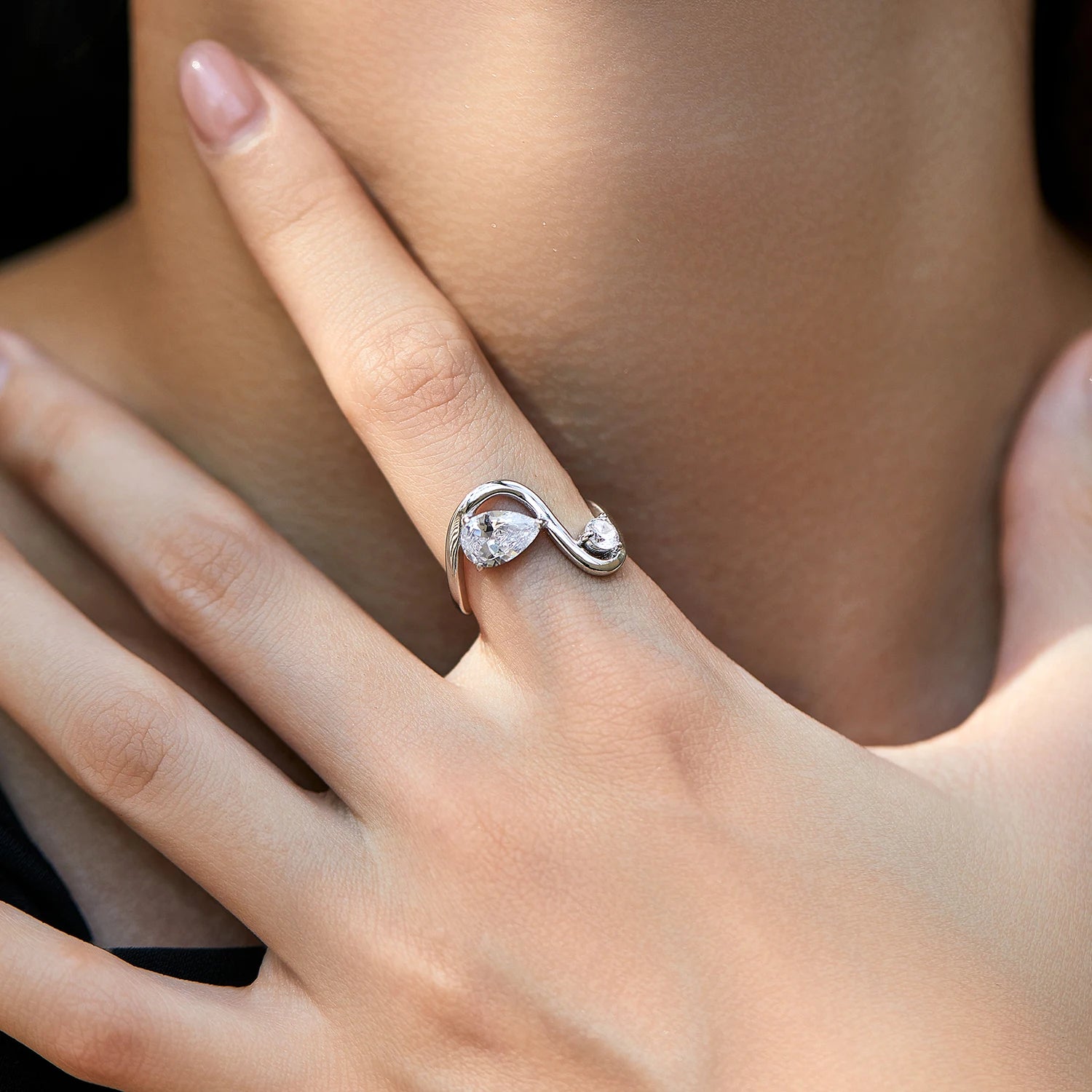 Sterling silver bypass ring featuring two white round-cut stones in a modern flowing design

