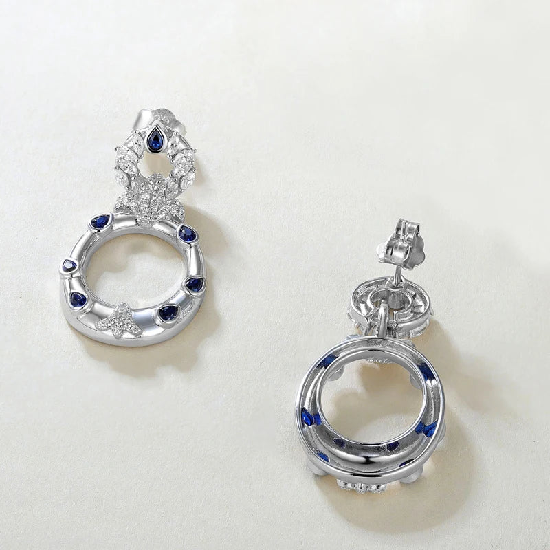 Sterling silver hoop earrings with blue teardrop stones and pavé crystal accents, inspired by underwater textures 
