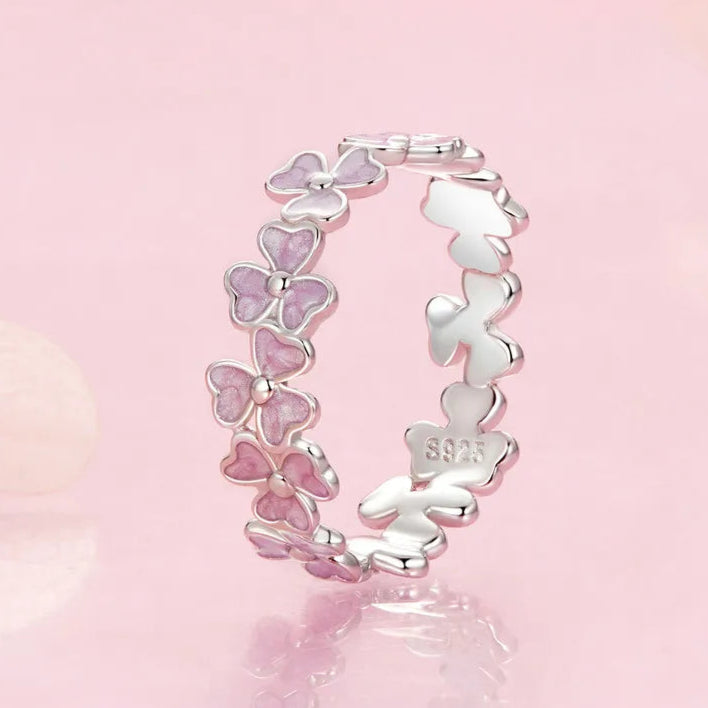 Delicate silver ring featuring small pink enamel flowers in a continuous garland design


