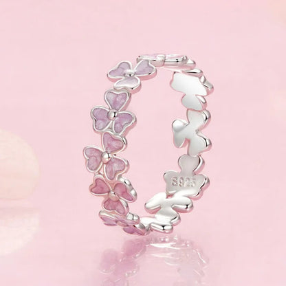 Delicate silver ring featuring small pink enamel flowers in a continuous garland design

