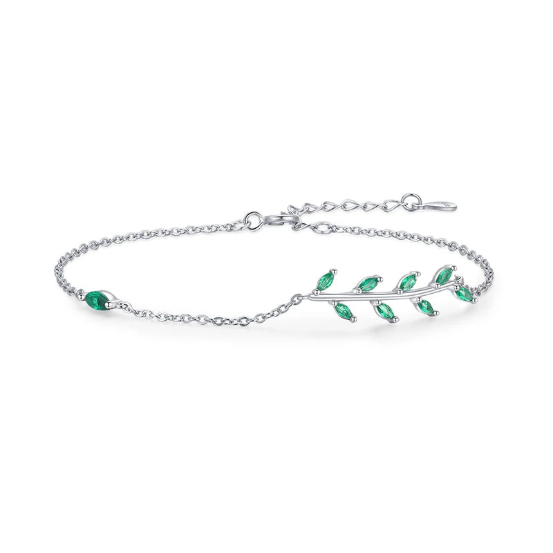 Gold chain bracelet with a delicate green leaf branch design.

