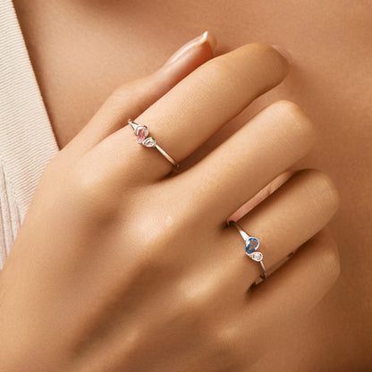 Sterling silver ring with a pear-shaped blue stone and round white stone set side by side
Sterling silver ring featuring a pink teardrop stone paired with a round clear stone in an open-heart inspired setting.



