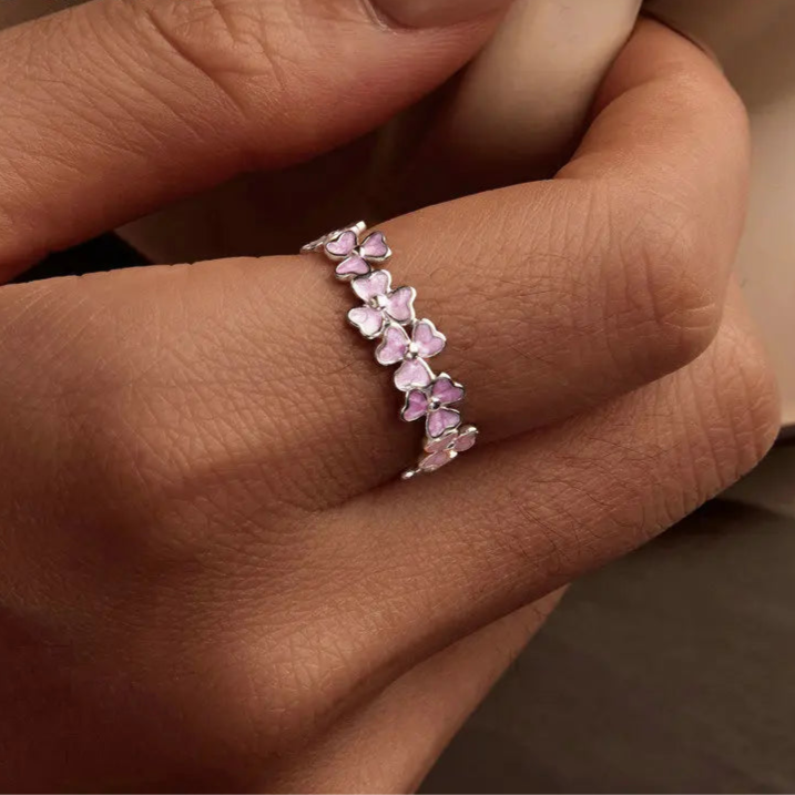 Delicate silver ring featuring small pink enamel flowers in a continuous garland design

