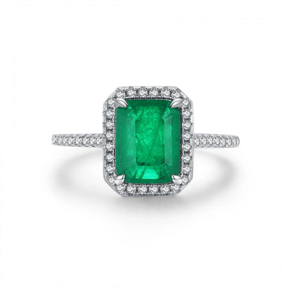 Rectangular green gemstone ring with a halo of clear stones on a silver band.

