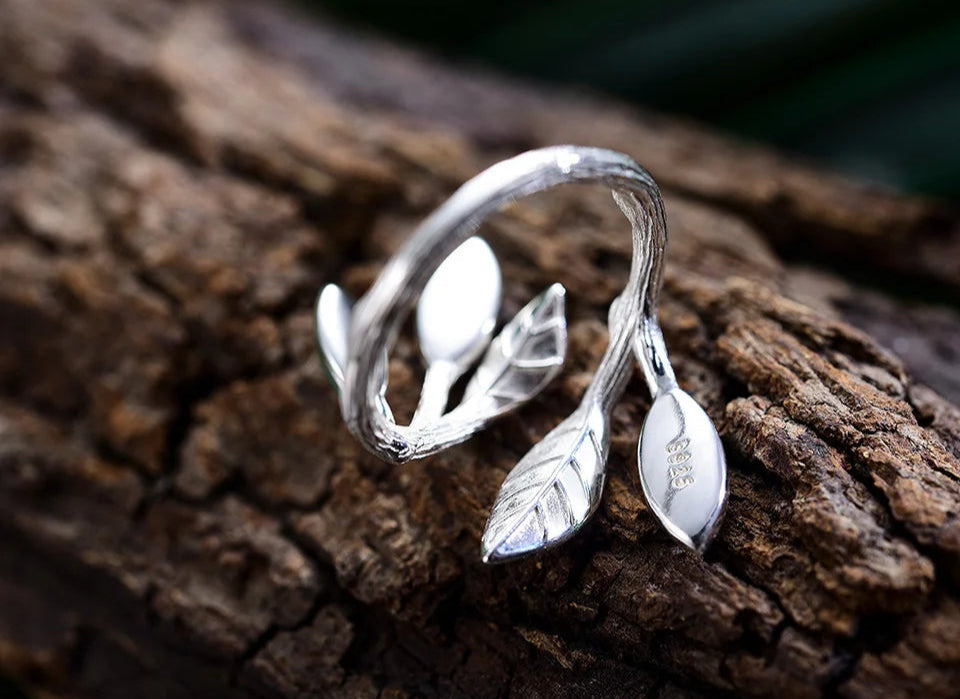 Adjustable silver ring featuring green marbled leaf accents in an open branch design.

