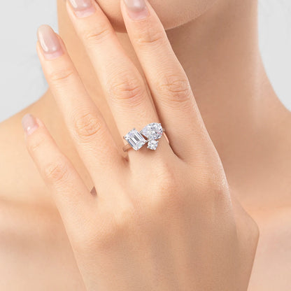 Silver ring with a mix of emerald, pear, and round-cut clear stones in an asymmetrical setting

